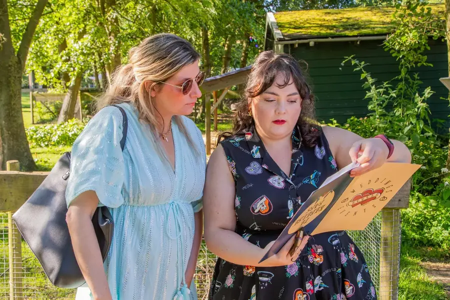 Twee vrouwen buigen zich in een tuin over een map met een rode print